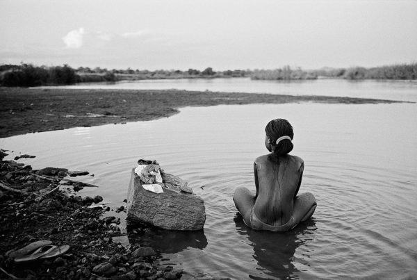 Photographie de collection noir et blanc de Marie Dorigny d'une jeune fille assise de dos dans un fleuve, Atelier Galerie Taylor à Paris