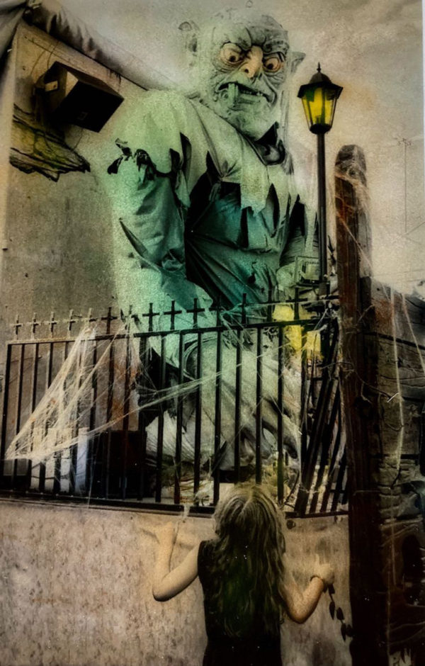 Photographie colorisée d'Irène Jonas d'une petite fille devant une attraction de monstre vert, Atelier Galerie Taylor à Paris.